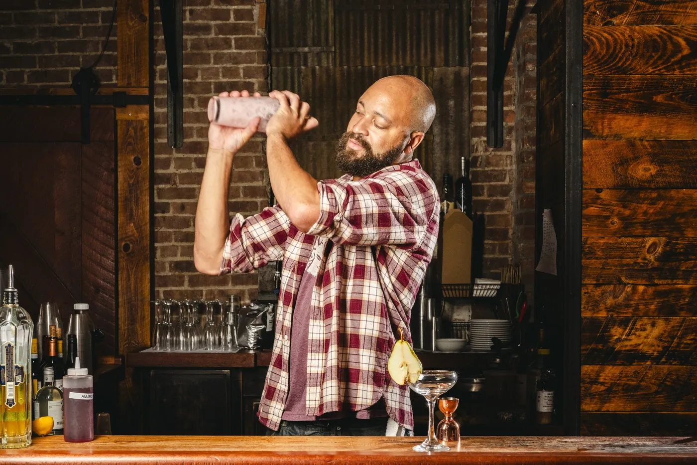 Bartender shaking a cocktail behind a brick and wood bar at Melzingah Tap House in Beacon