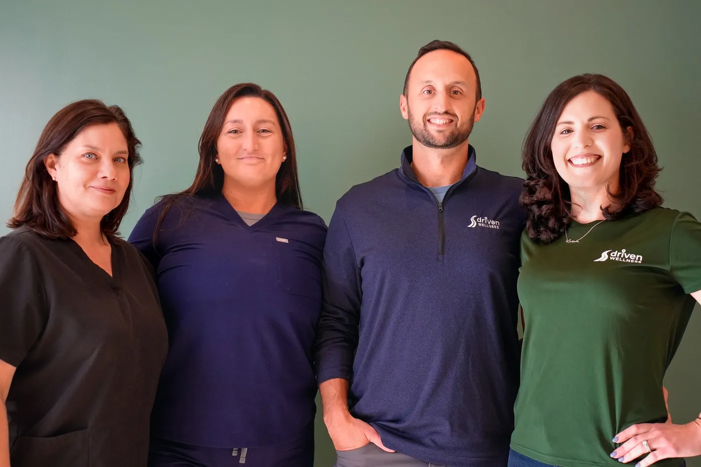 Team portrait of four staff members in branded shirts