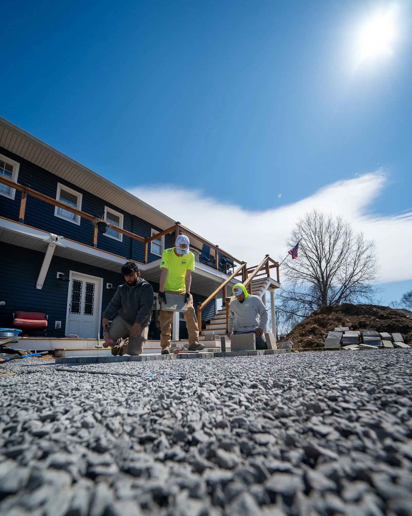 Landscaping crew laying gravel patio in front of Hudson Valley home, construction photography
